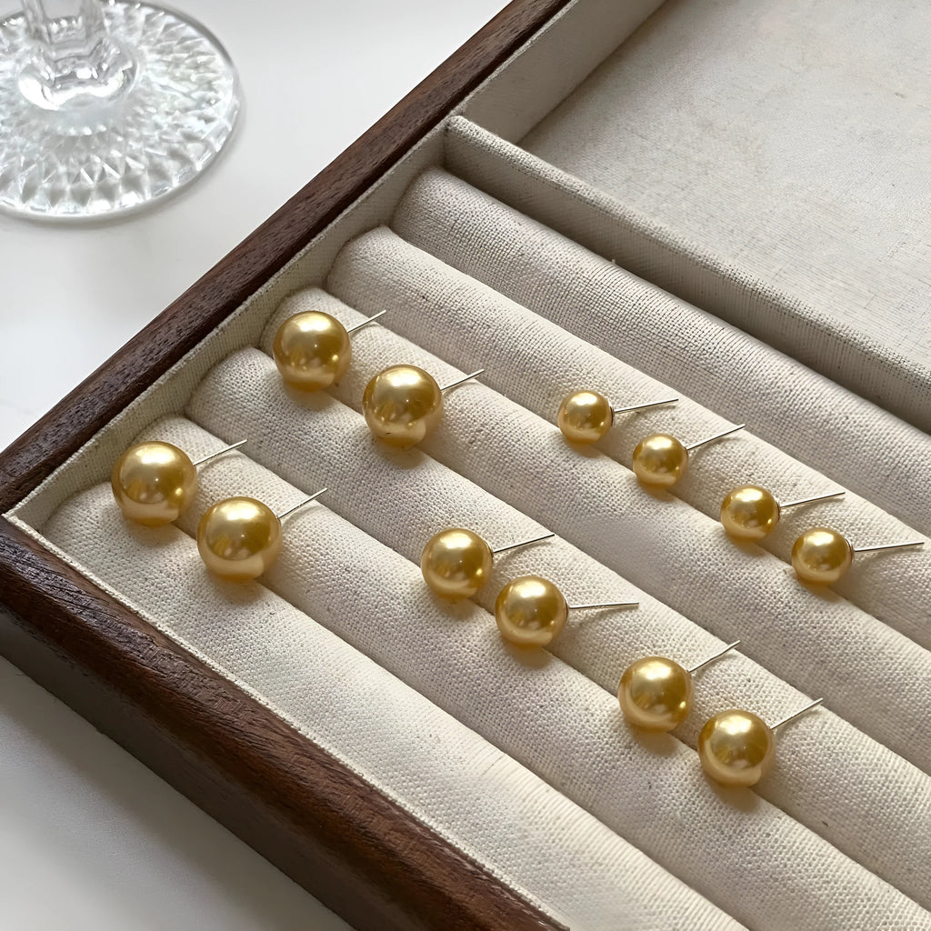 A pair of large pearl stud earrings with a geometric silver setting and an eight-awh star detail on a white background.