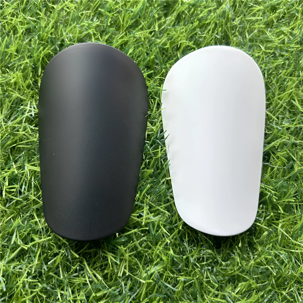 Extra small plastic football shin guards in black and white, measuring 8x5cm