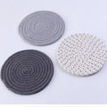 Three round cotton cord coasters in blue colour set on wooden table