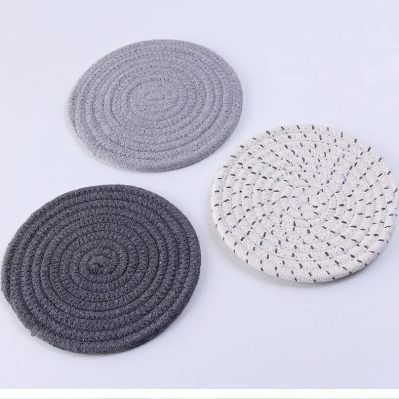 Three round cotton cord coasters in blue colour set on wooden table