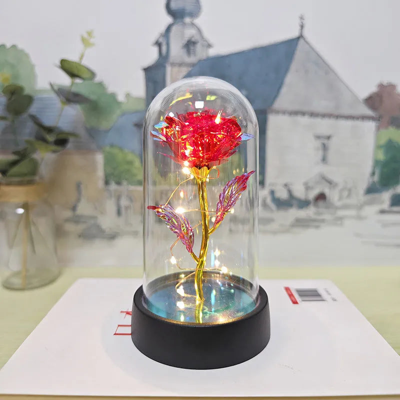 Small decorative night lamp with glass cover and plastic flowers, showing coloured light illumination.