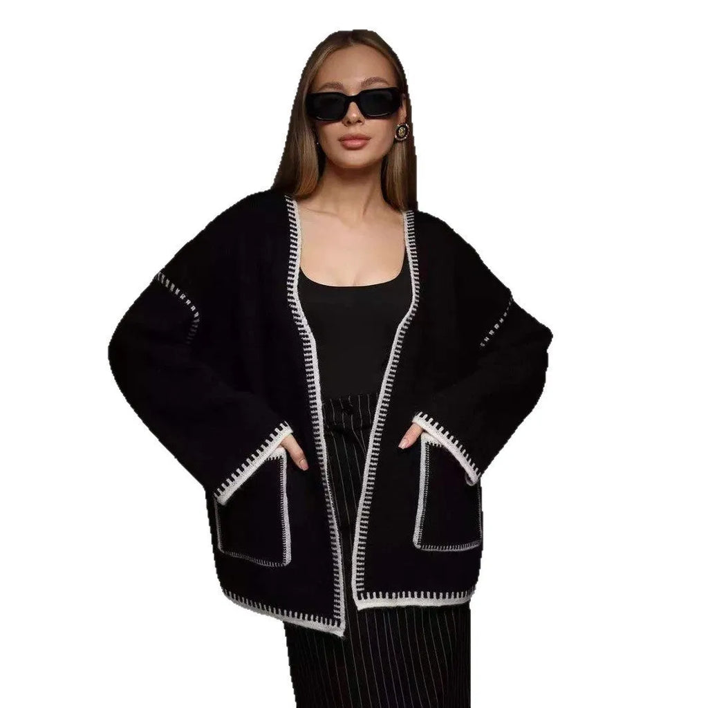 Loose grey knitted cardigan with lace-up front ties on a hanger.