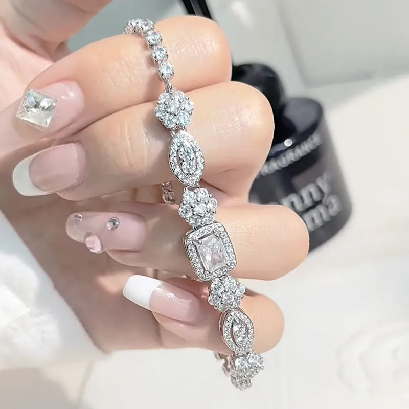 Women's geometric silver and white gold plated bracelet with inlaid zircon stones on a model's wrist.
