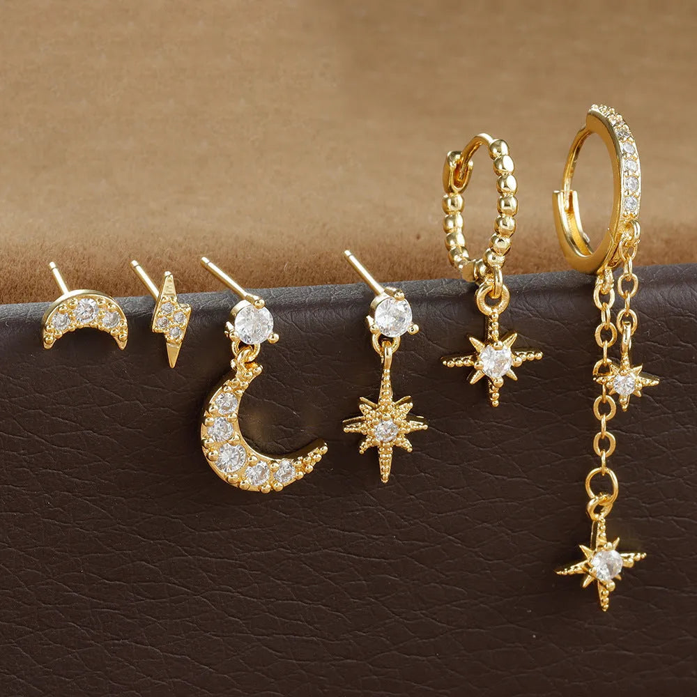 Set of six gold chain tassel drop earrings with crystal studs on a white background.