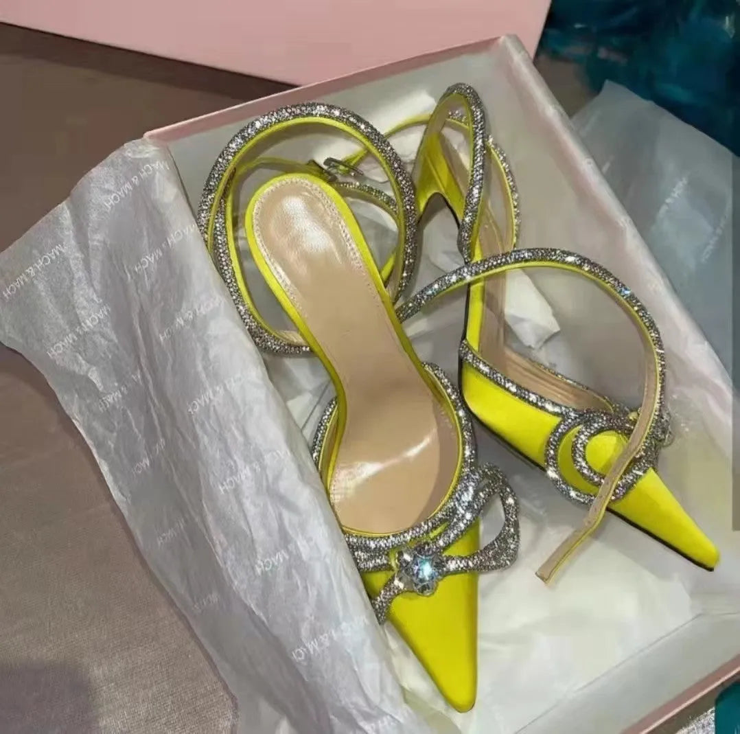 Women's black stiletto heel sandals with a silk bandage strap and buckle fastening on a pointed toe.
