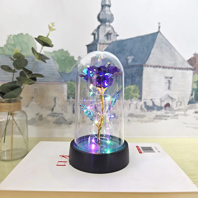 Small decorative night lamp with glass cover and plastic flowers, showing coloured light illumination.