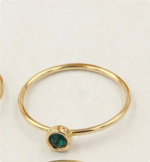 Women's copper knuckle ring with gilded finish and zircon stones in green, blue, red, and white.