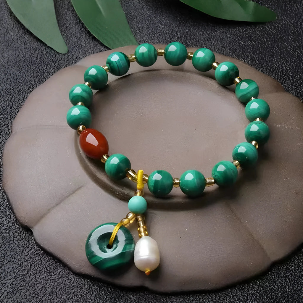 Handmade natural malachite and red agate stone bead bracelet on a wrist.