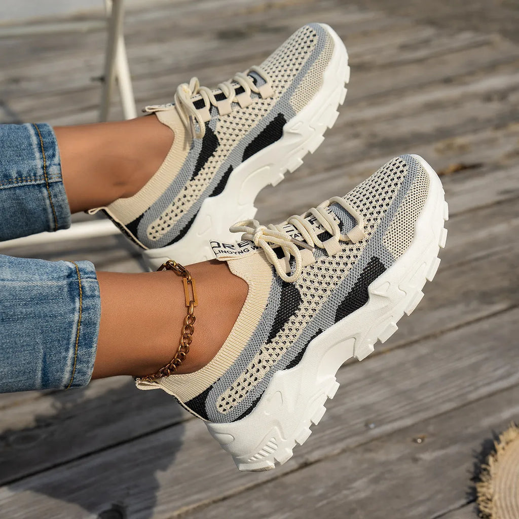 Women's Flyknit mesh sneakers in grey and white with a flat rubber sole and lace-up front.