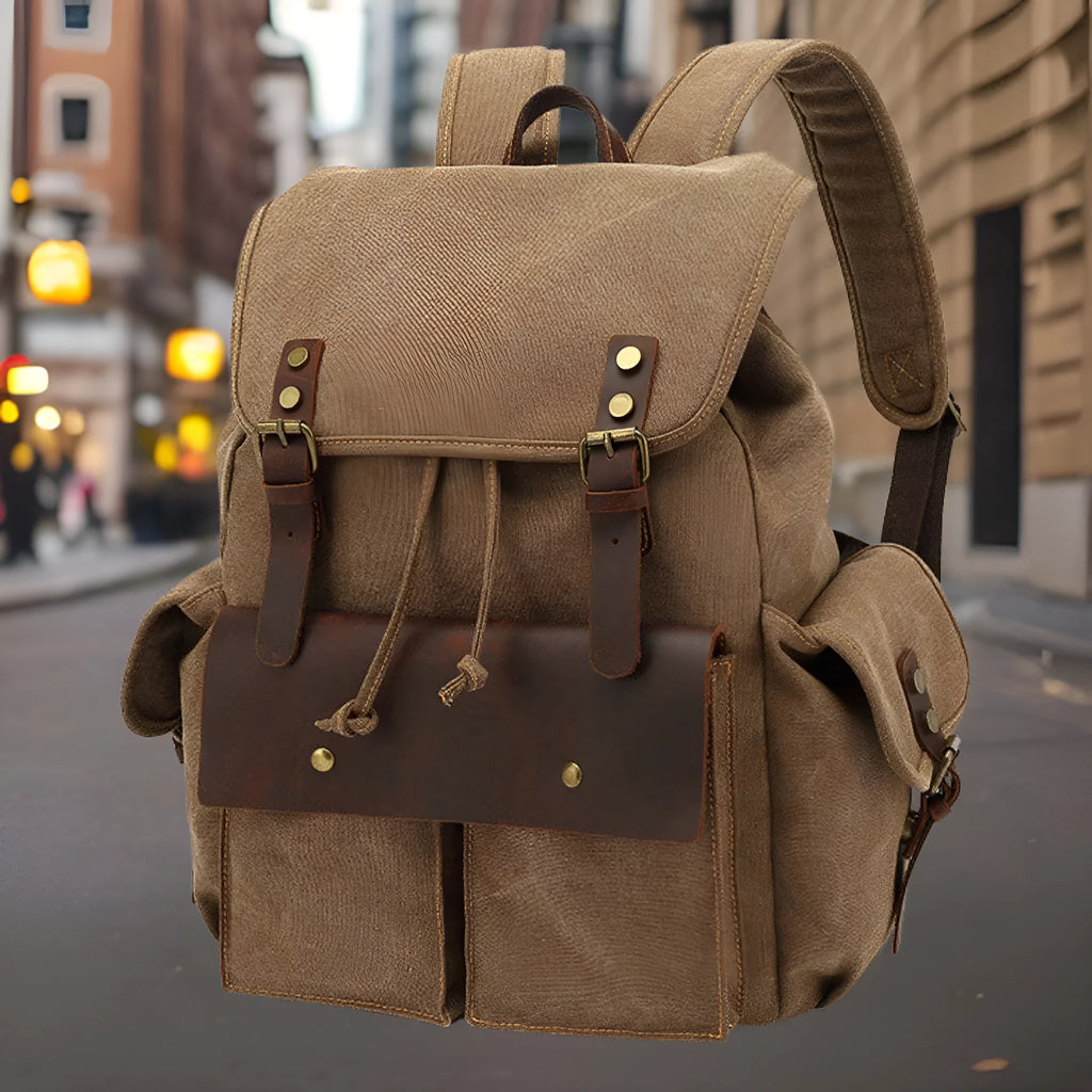 Retro canvas backpack in army green colour with antique bronze hardware, shown with a laptop to scale.