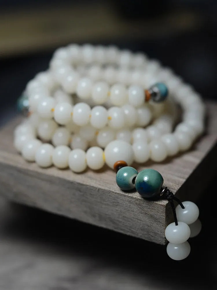 White jade bodhi seed bracelet with 108 flat round beads on a wrist.
