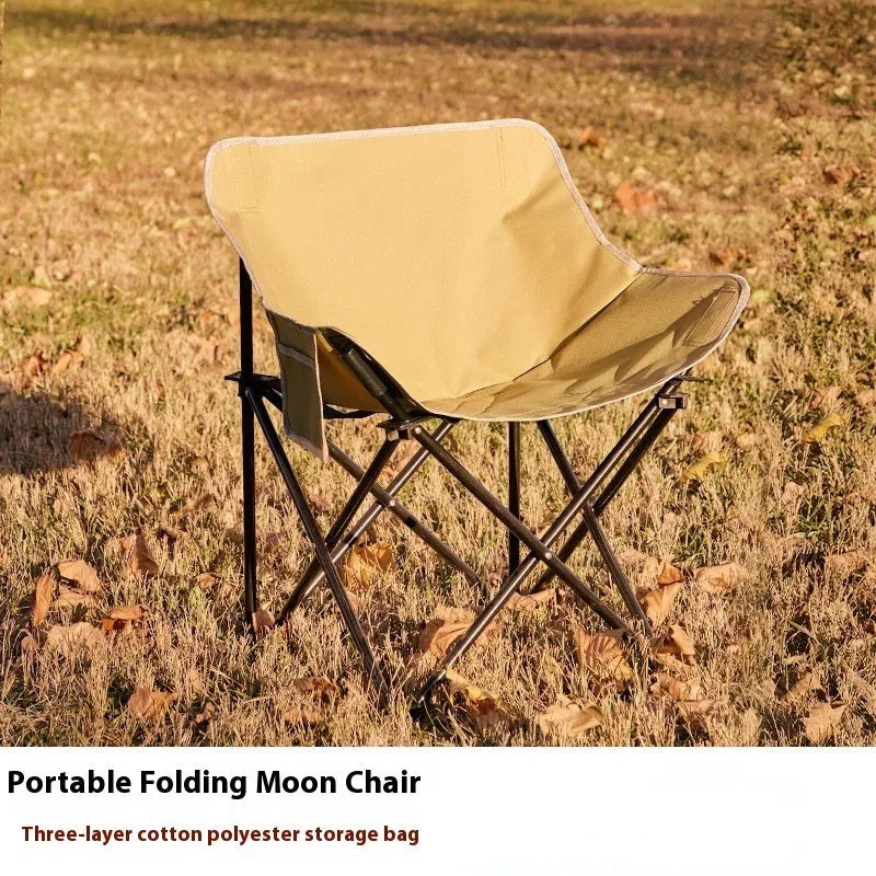 Beige folding camping chair with reclined back and steel frame on grass.
