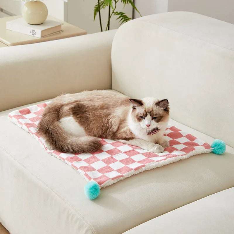 Green plaid plush fleece pet blanket with fur ball trim, laid flat as a dog bed or cat mat.