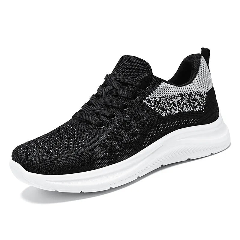 Women's low-top black mesh sneakers with white laces and a round toe on a grey background.