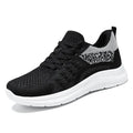 Women's low-top black mesh sneakers with white laces and a round toe on a grey background.