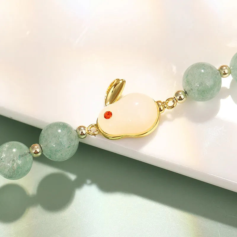 Green aventurine and strawberry quartz rabbit charm bracelet on a copper and gold chain.