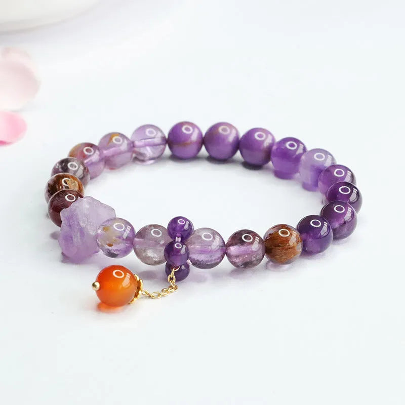 Close-up of a nine purple Fire Duobao and amethyst crystal bracelet with red agate stones, Mori style.