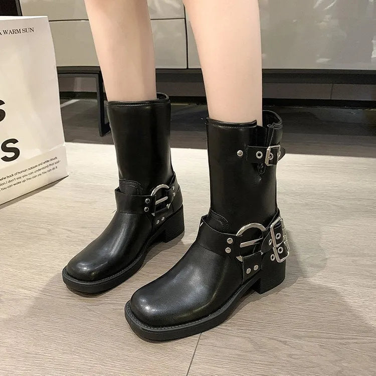 Women's black mid-calf platform boots featuring a large belt buckle on the shaft.