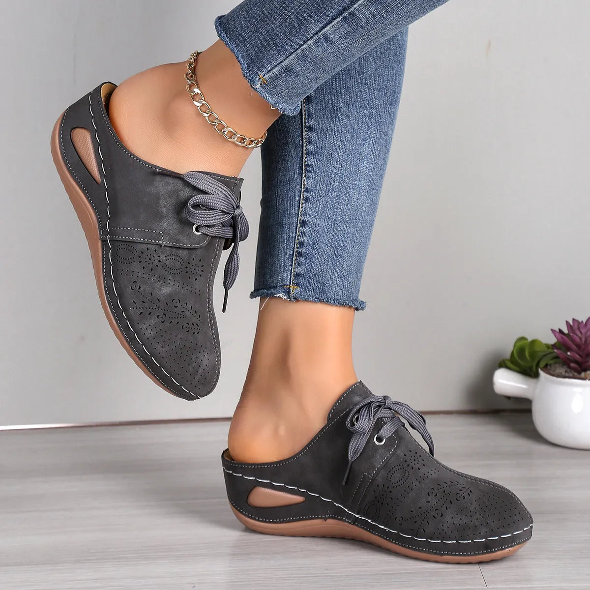 Women's black lace-up baotou slippers with a suede upper and rubber sole on a neutral background.