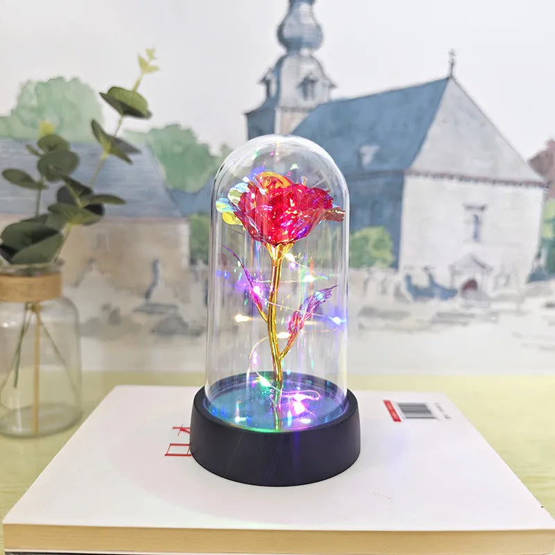 Small decorative night lamp with glass cover and plastic flowers, showing coloured light illumination.