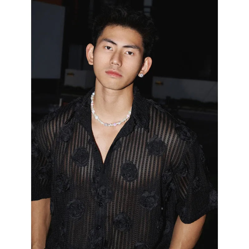 Man wearing a loose-fit black short-sleeved shirt with a large white three-dimensional floral print.