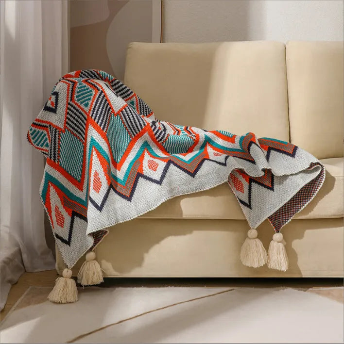 Acrylic sofa blanket with tassel fringe in neutral beige tone on grey sofa