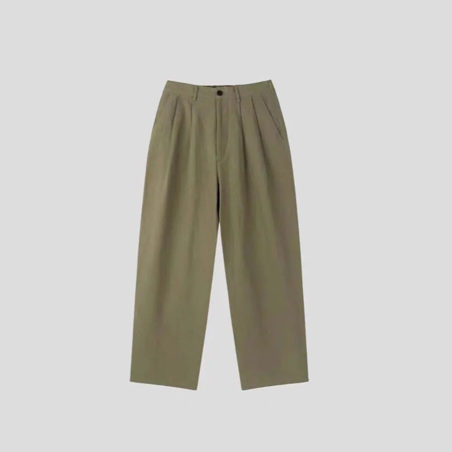 Men's apricot coloured loose-fit cotton linen trousers with a pencil leg on a plain background