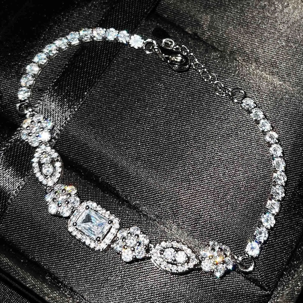 Women's geometric silver and white gold plated bracelet with inlaid zircon stones on a model's wrist.