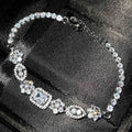 Women's geometric silver and white gold plated bracelet with inlaid zircon stones on a model's wrist.