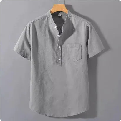 A man's casual beige slub linen shirt with a stand collar and short sleeves, laid flat to show its loose fit.
