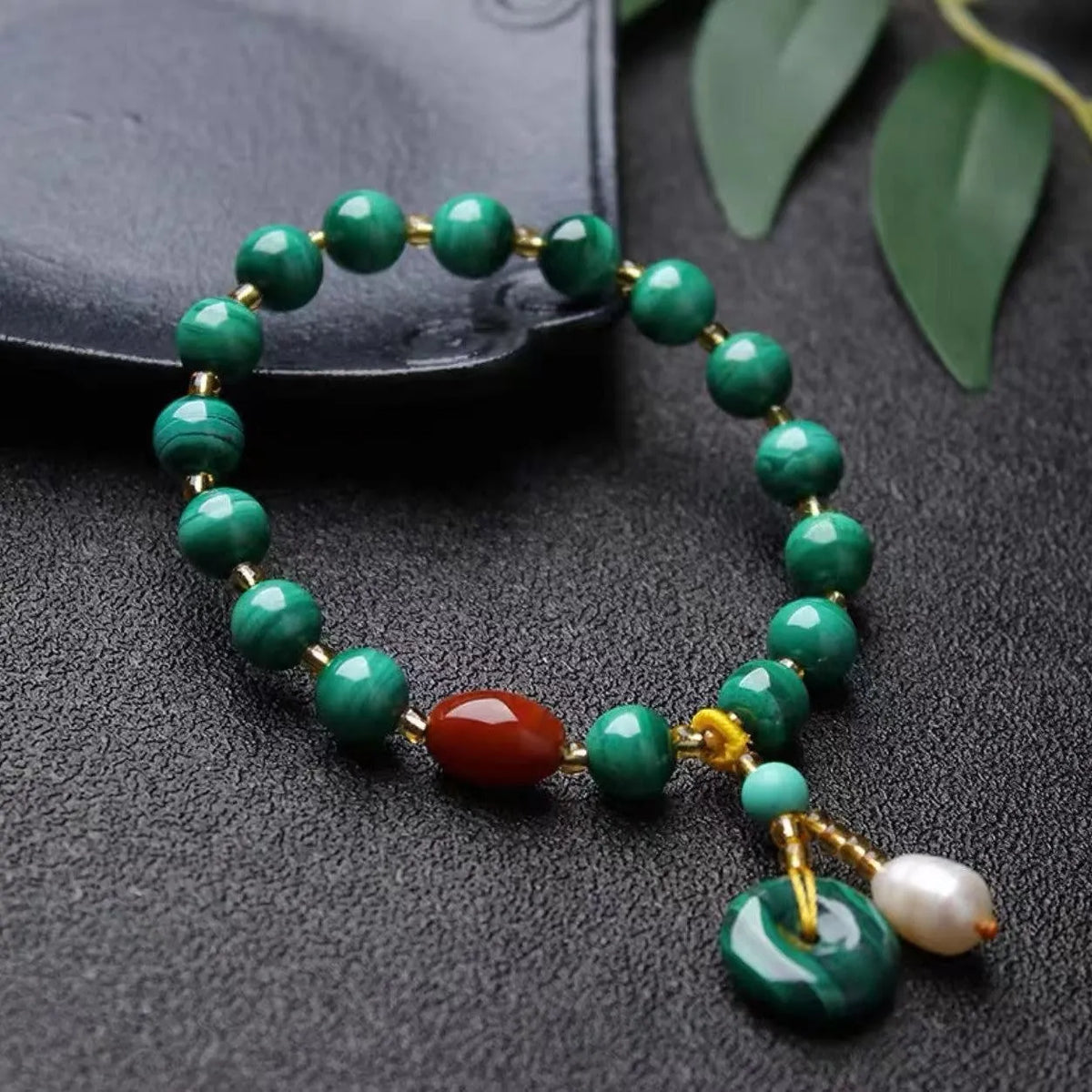 Handmade natural malachite and red agate stone bead bracelet on a wrist.