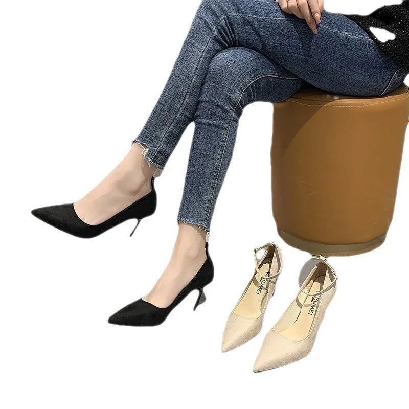Women's black stiletto heel pump shoe with buckle detail on a white background.
