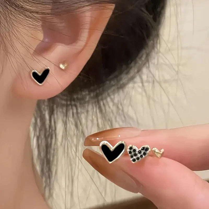 Three pairs of heart shape alloy earrings in gold, black, black white, and pink colours with love design elements