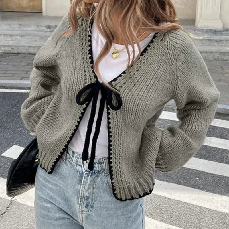 Gray lace-up front cardigan with crocheted flower detail on a model, showing loose long sleeves.