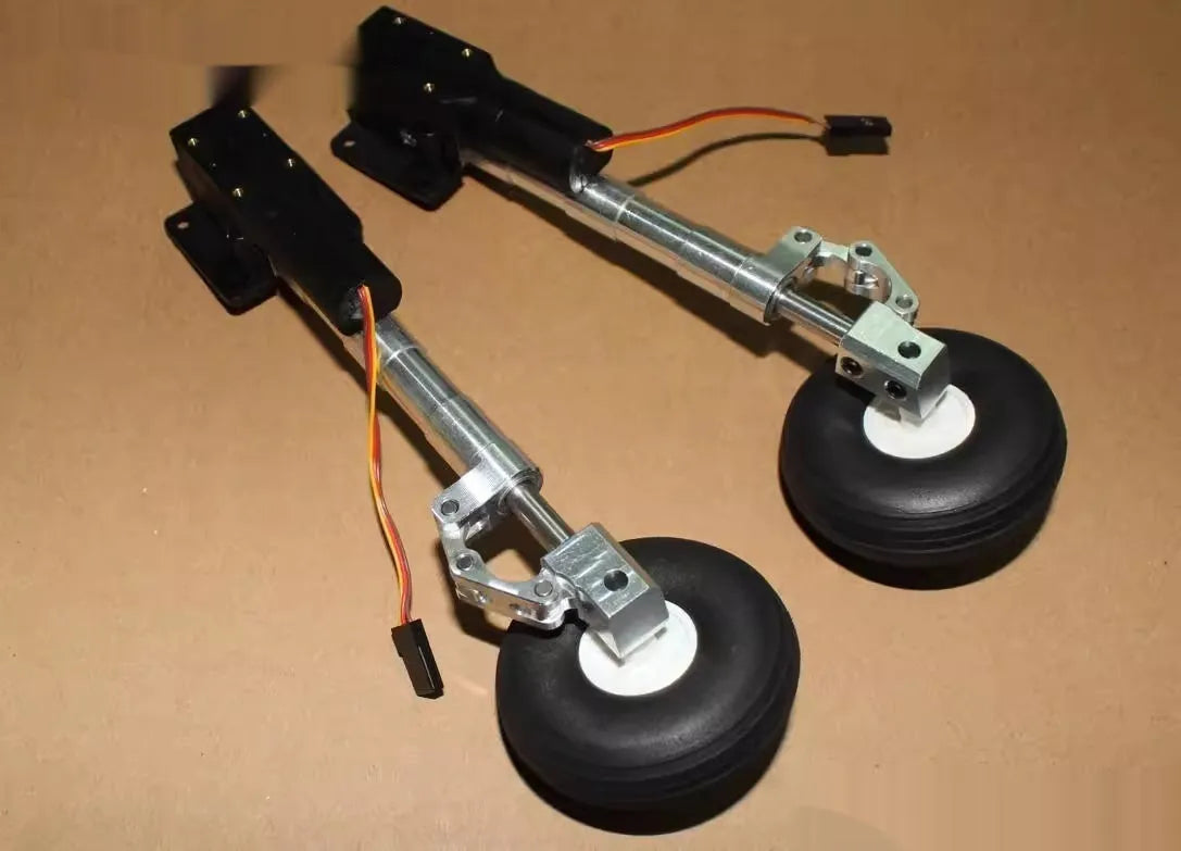 Pair of silver alloy retractable landing gear with shock absorbers and black rubber wheels for RC model aircraft.