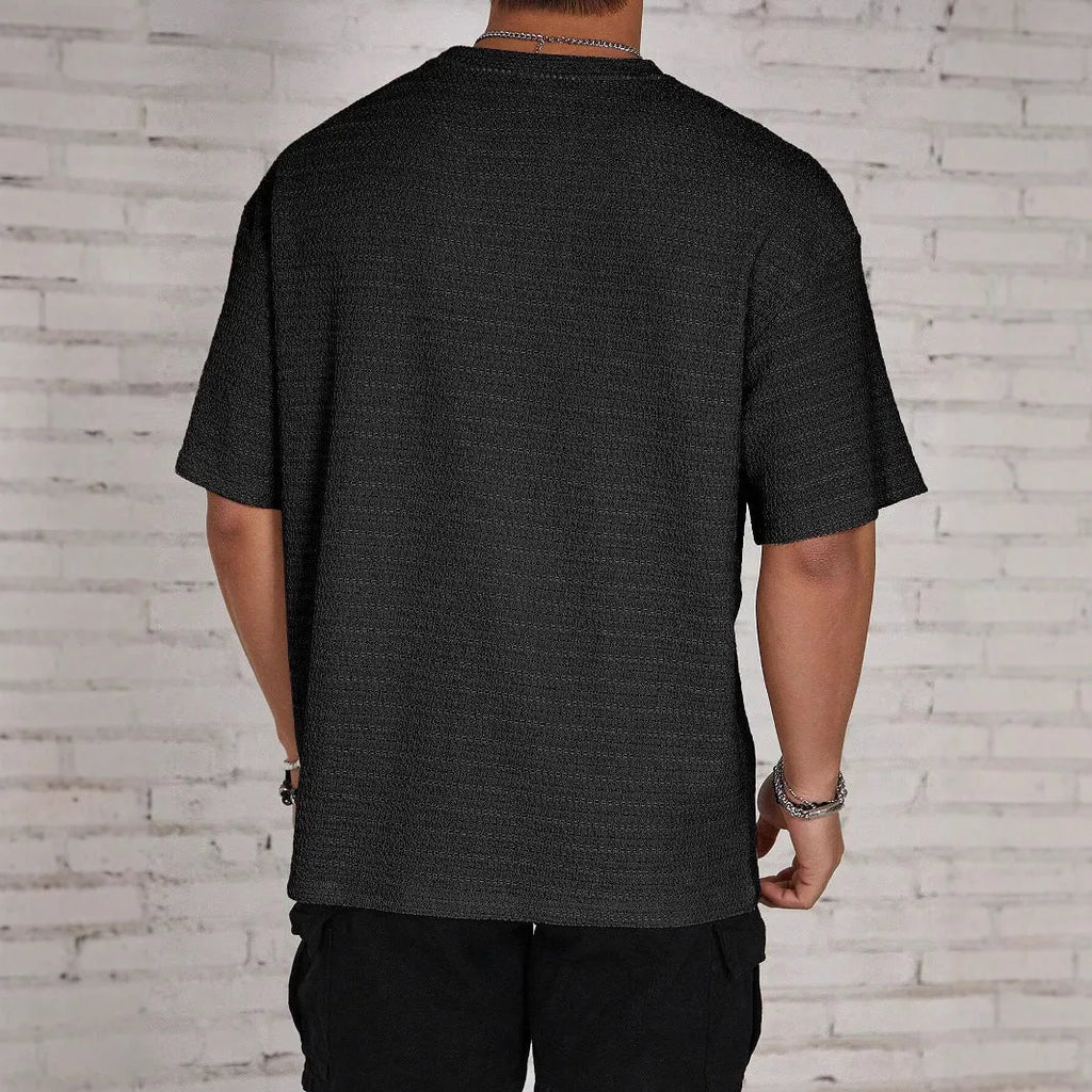 Men's loose fit solid colour round neck t-shirt in polyester on a neutral background.