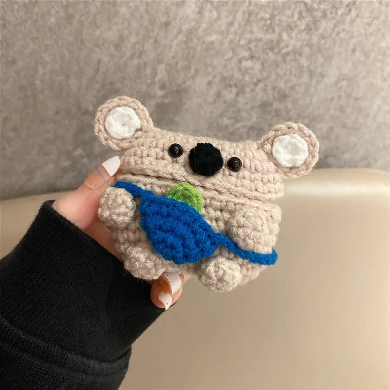 Handmade knitted koala bear backpack cover for AirPods charging case on a table.