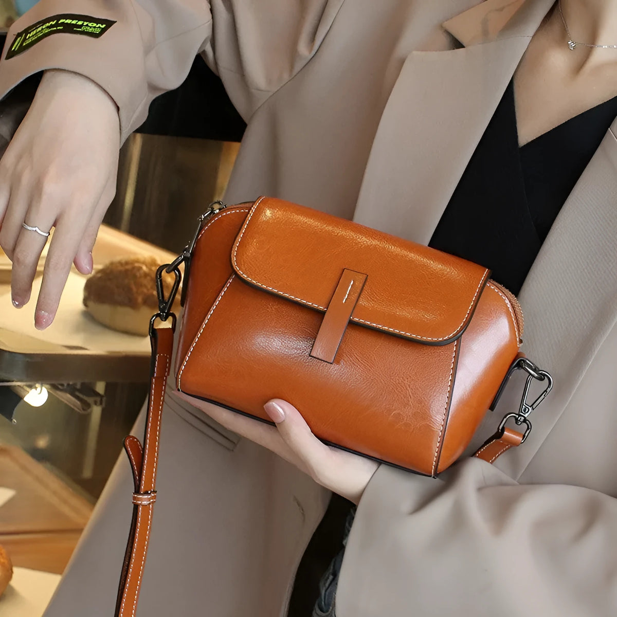 Brown women's genuine leather messenger bag with cross-body strap, showing outer sandwich pocket and visible sewing detail.