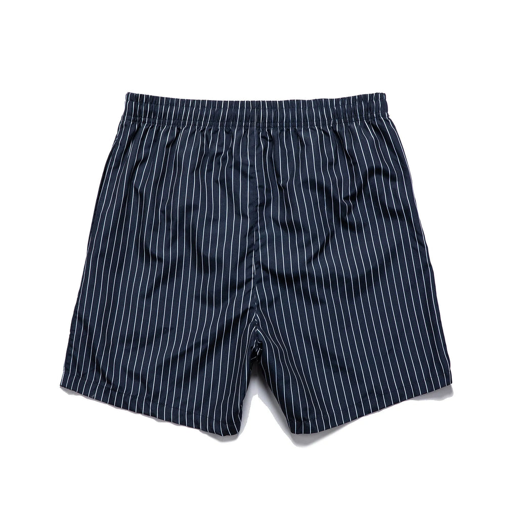 Man or woman wearing striped polyester shorts in navy blue, straight leg style, for beachwear.