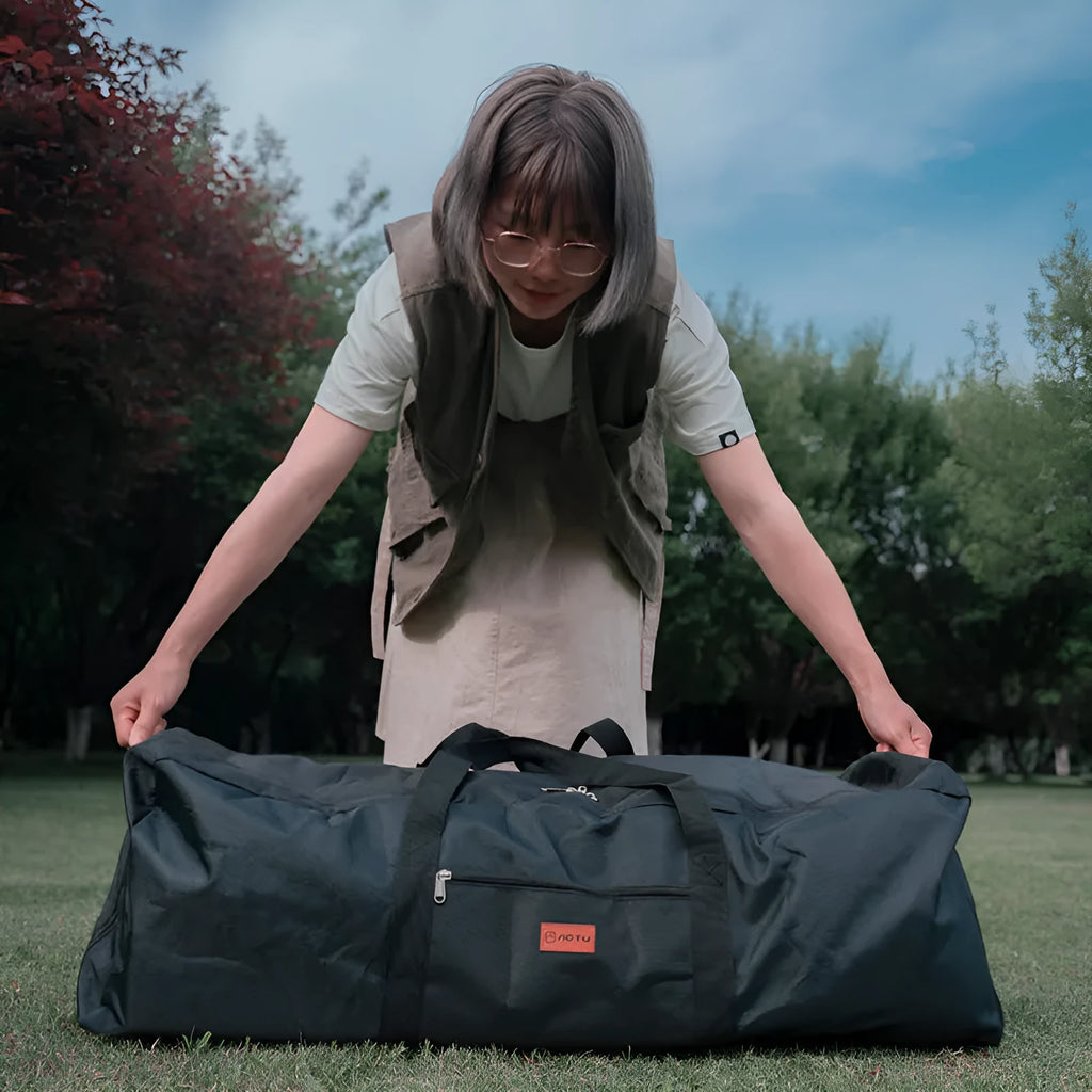 Large black waterproof storage bag with carrying handles, shown next to a folded camping chair.