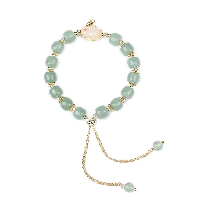 Green aventurine and strawberry quartz rabbit charm bracelet on a copper and gold chain.