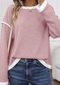 Woman wearing a loose drop shoulder knit top with contrast trim, shown in beige, light pink, and four leaf clover print colours.