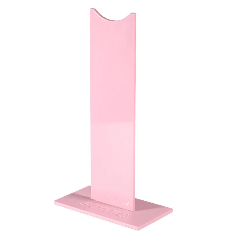 Pink and black detachable headphone stand with silicone base on a desk.