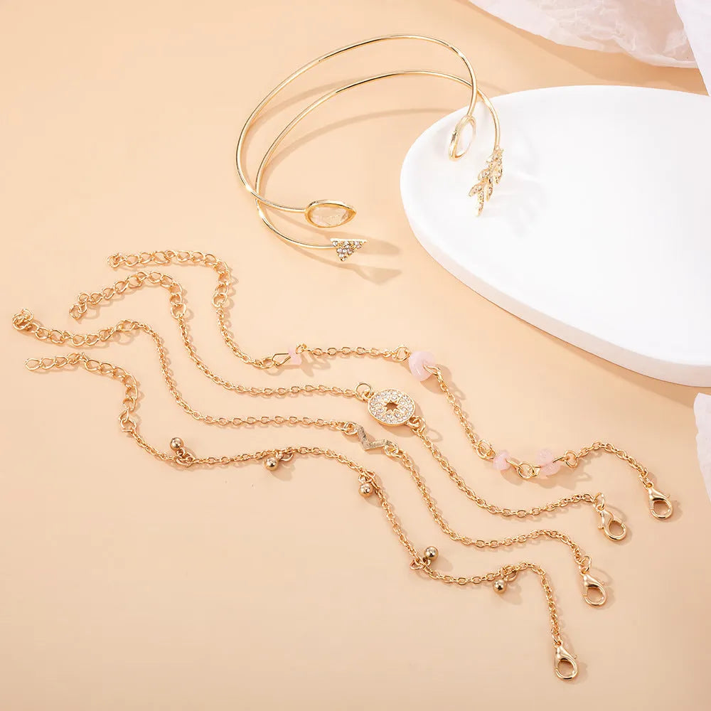 Set of six golden bracelets with arrow, water drop and V shapes featuring spot drill pattern.
