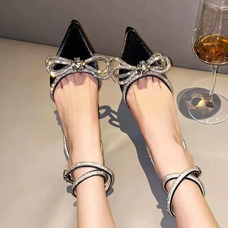 Women's black stiletto heel sandals with a silk bandage strap and buckle fastening on a pointed toe.