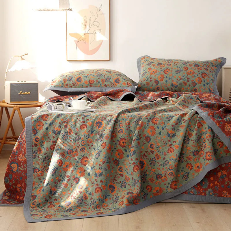 Cotton gauze floral blanket and two pillowcases set laid on a bed, showing plants and flowers pattern.
