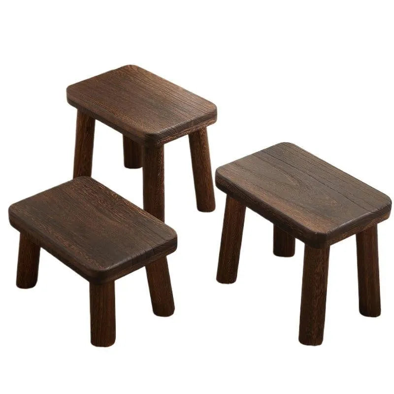 Solid wood changing stool with distressed finish and bracket legs in a living room setting.