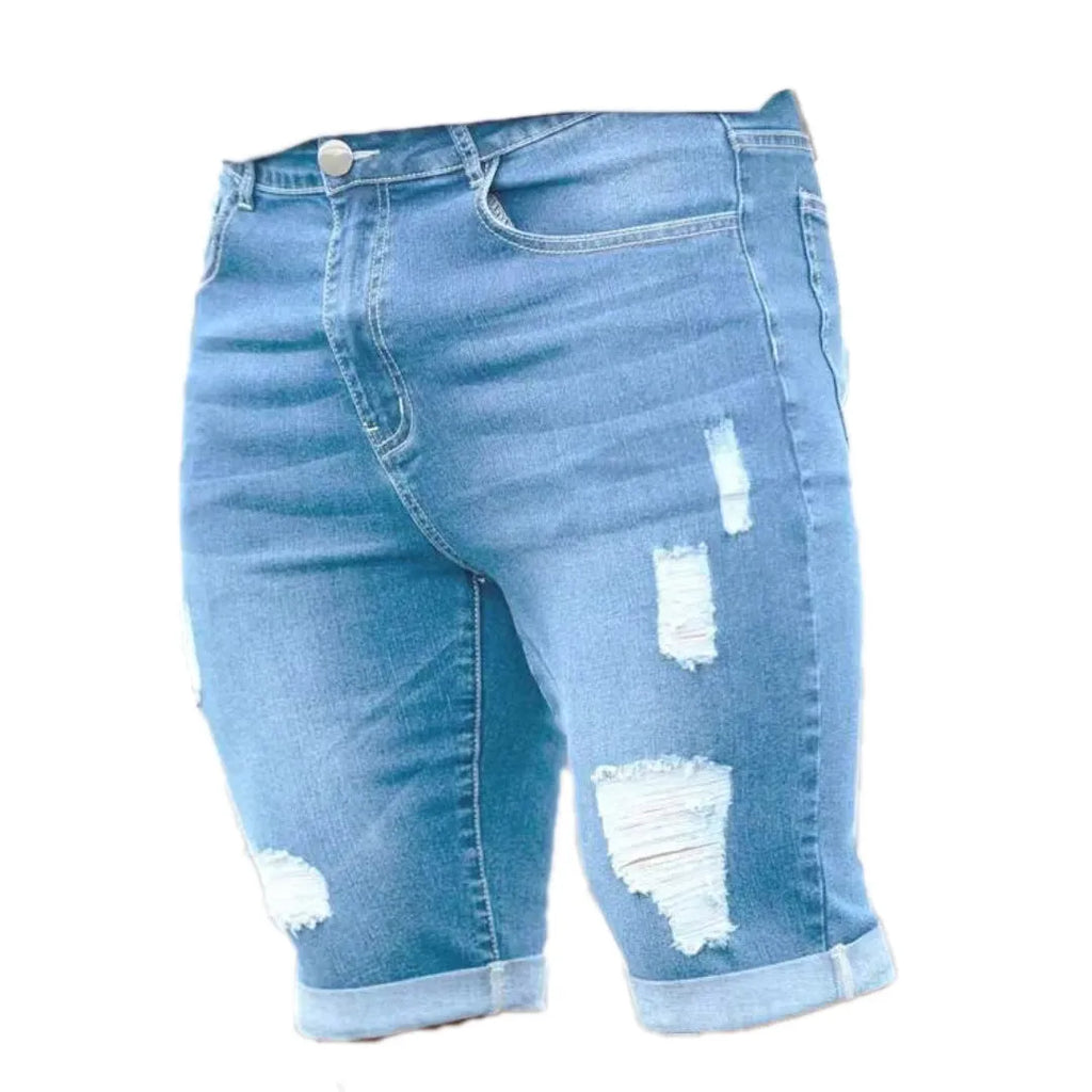 Sky blue men's denim shorts with multi-hole distressing on the legs, showing a low-rise waist and zipper fly.