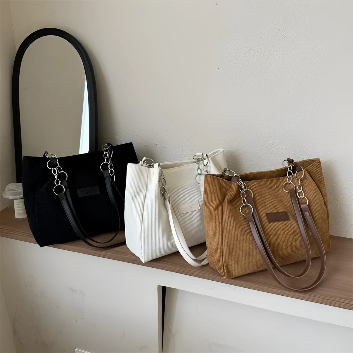 Corduroy one-shoulder tote handbag in black, showing three-dimensional pockets and a large main compartment.