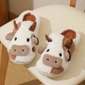 White and coffee coloured cow-themed plush slippers for women with a textured non-slip sole.